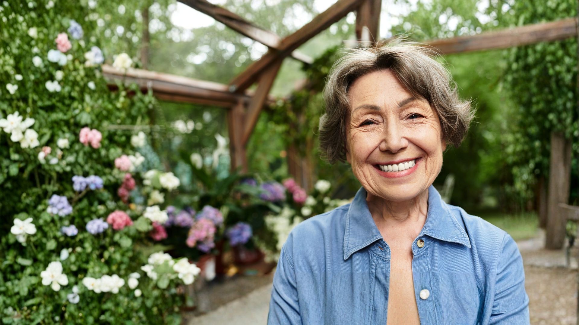 A smiling older woman in a sunny garden